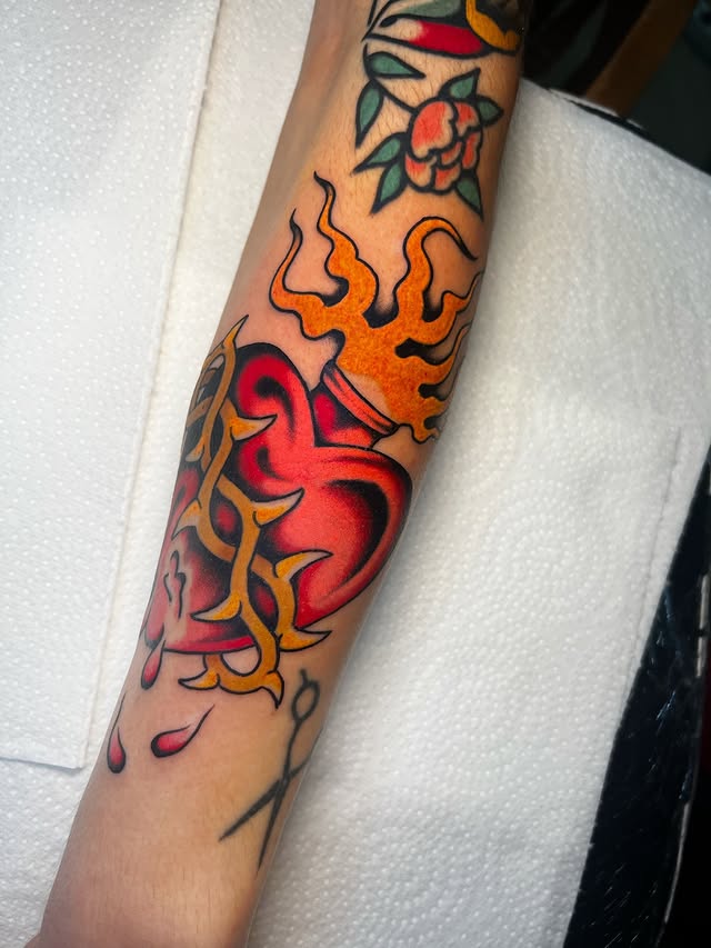 tatuaje corazon con fuego y espinas estilo tradicional a color
